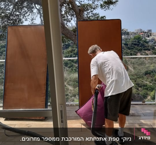 אדם מנקה ספה עם שואב אבק על מרפסת